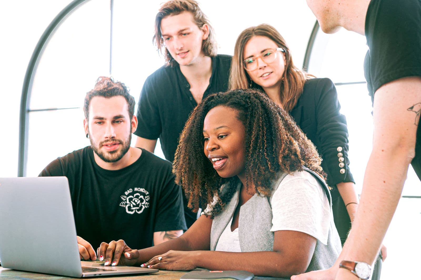 A diverse team led by a Black woman studying insights together on a laptop in a bright modern space