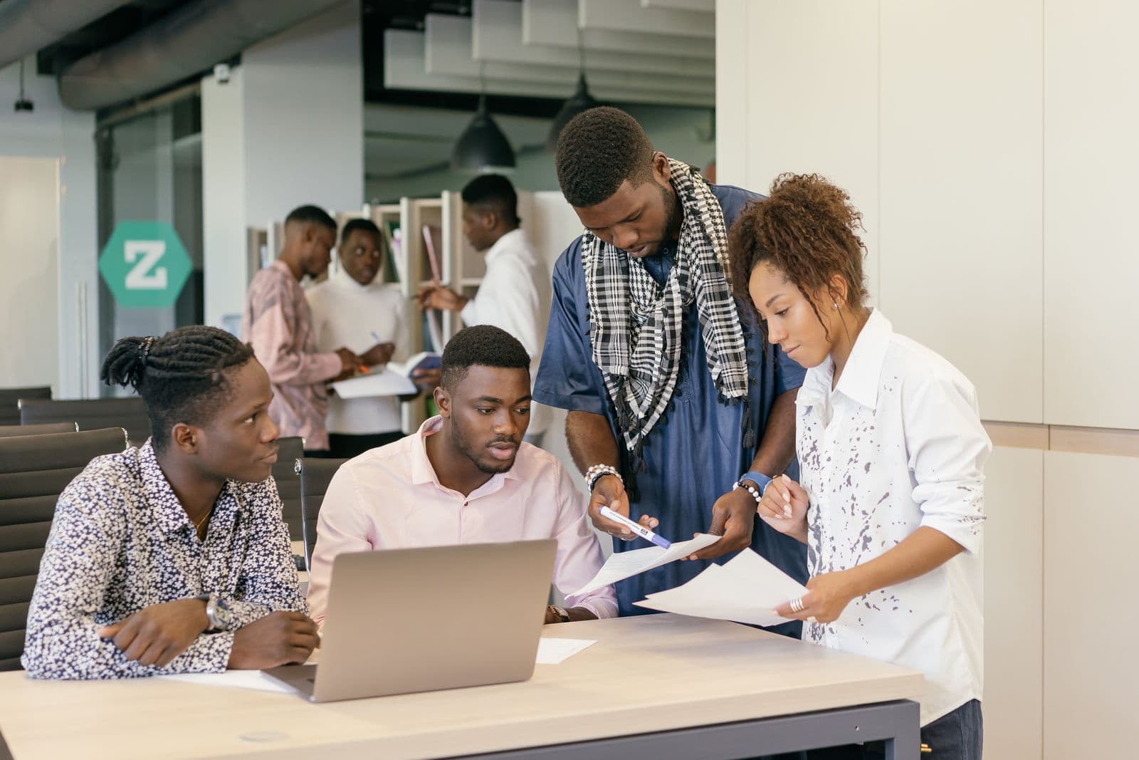 A predominantly Black African team implementing together over a laptop in a modern office