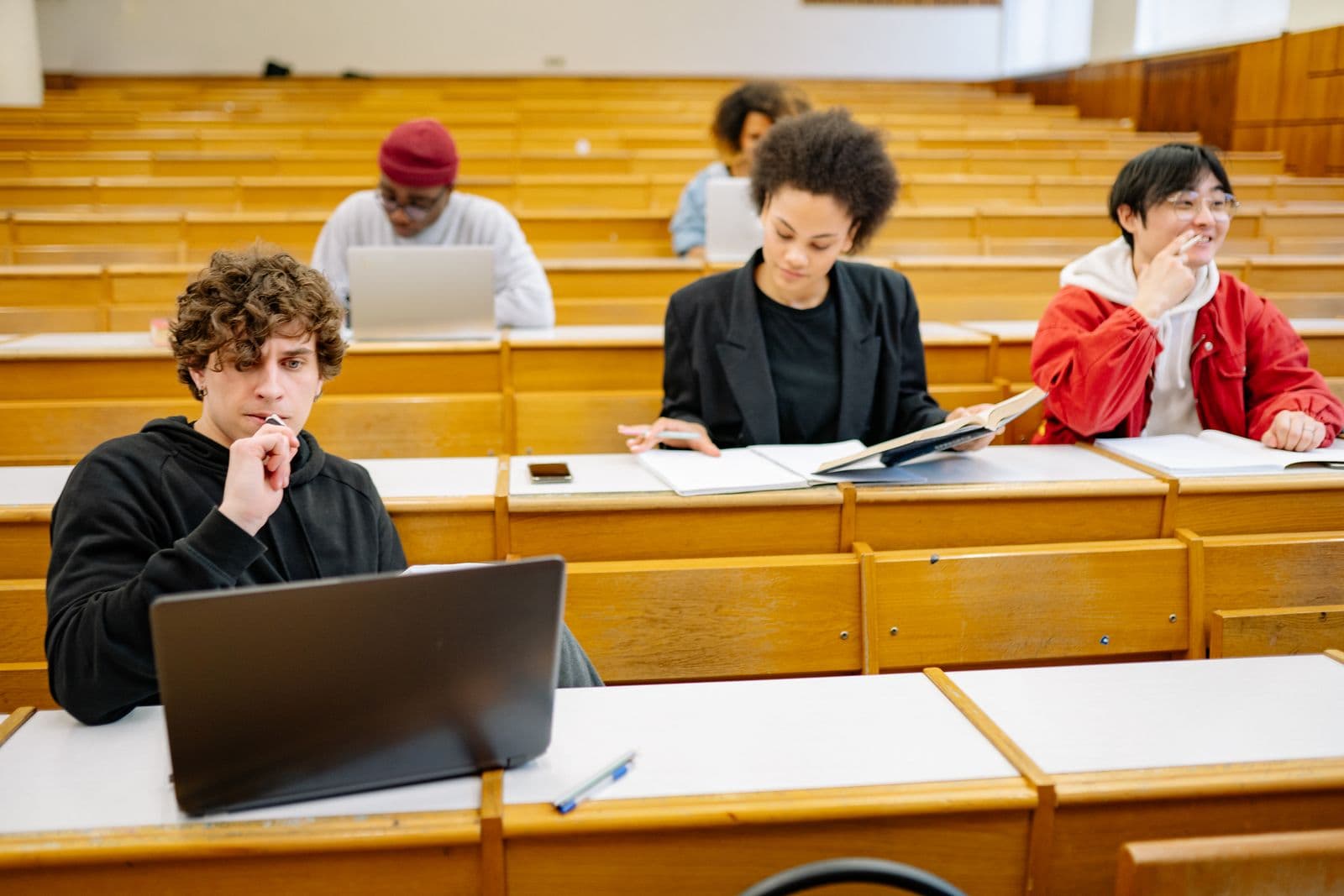 A diverse group of advanced learners — Black, mixed-heritage, Asian and white — studying in a modern university lecture hall