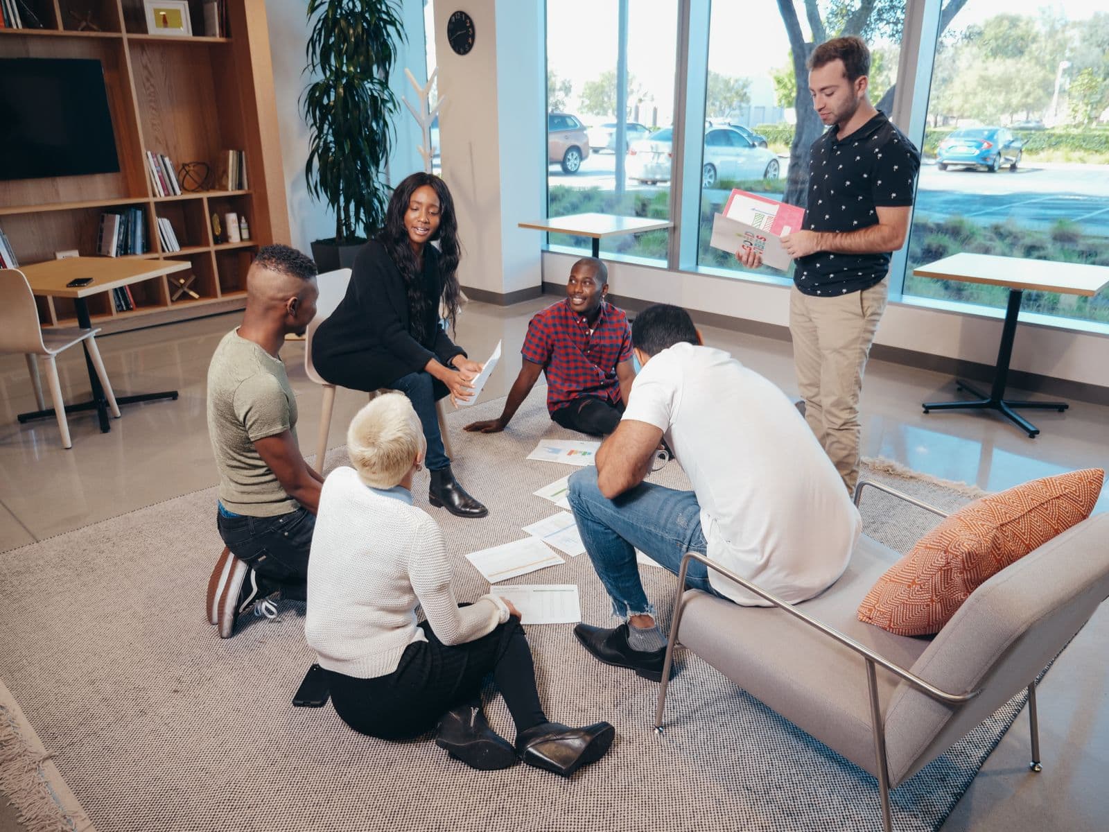 A predominantly Black African team — led by a Black woman, with Black, white and mixed-heritage colleagues — collaborating over research notes in a bright modern workspace